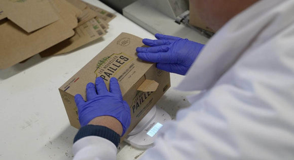 Person packaging eco-friendly bagasse straws in a brown box for sustainable cocktails.